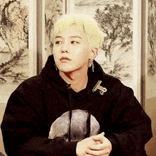 a young man with blonde hair is wearing a black sweatshirt