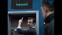 a man with a mustache is pointing at a sign that says vanssi