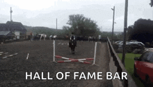a horse is jumping over a hurdle with the words hall of fame bar behind it