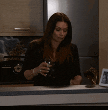 a woman sitting at a counter with a glass of water in her hand