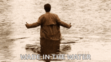 a man is standing in a body of water with the words wade in the water below him
