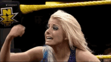 a woman is flexing her muscles in a wrestling ring while wearing a purple top .