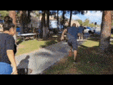 a man is running down a sidewalk in a park while a woman watches .