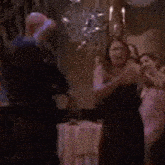 a group of people are dancing in a room with a table .