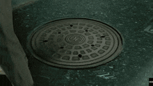 a manhole cover is open and a woman is walking in the background
