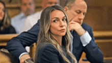 a woman and a man are sitting in a courtroom .