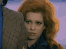 a woman with red hair is standing next to a man in a plaid jacket