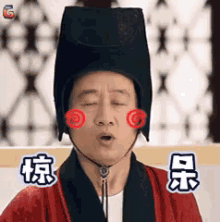 a man is wearing a black hat and a red robe .