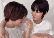 two young men are hugging each other and one of them has km1 ver.du written on his shirt