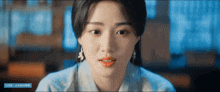 a close up of a woman 's face with a blue banner behind her that says ' a ' on it