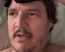 a close up of a man 's face with a beard and mustache wearing a hat .