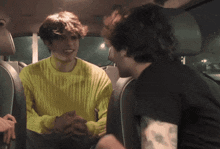 a man in a yellow sweater is talking to another man in a car