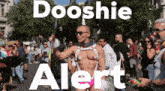 a man in a leather harness stands in front of a crowd with the words dooshie alert on the bottom