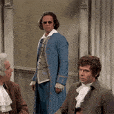 a man in a blue coat and sunglasses is standing next to two other men