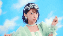 a woman wearing a green dress and a tiara is standing in front of a blue sky