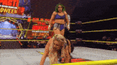 two women are wrestling in a ring with a sign that says halloween .