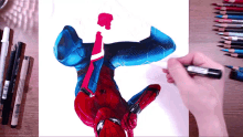 a person is drawing a picture of a spiderman with a marker