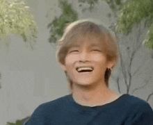 a young man is covering his mouth with his hand and laughing .