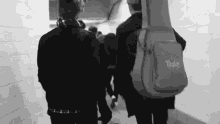 a black and white photo of a group of people walking down a hallway .