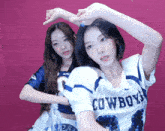 a girl wearing a cowboys jersey stands next to another girl