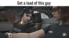 a man in a s.w.a.t vest talks to a woman in a car