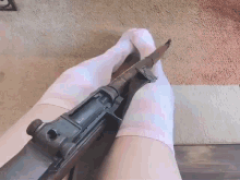a person wearing pink socks is holding a gun between their legs .