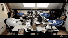a group of people are sitting at desks in front of computer monitors