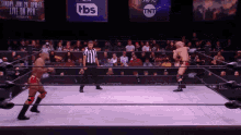 a wrestler in a ring with tbs and tnt banners behind him
