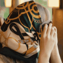 a person covering their face with a scarf that says oooo
