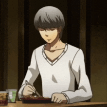 a man is sitting at a table eating food with chopsticks and a fork .