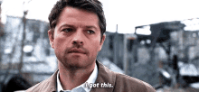 a man in a suit and tie is standing in front of a building and saying `` i got this . ''