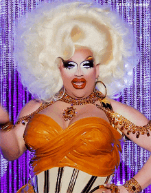 a drag queen with a huge white wig and a gold corset