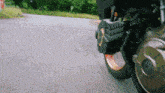 a motorcycle is driving down a road with a few trees in the background