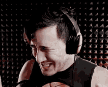 a man wearing headphones is holding a basketball and smiling in front of a microphone .