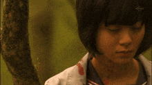 a girl with blood on her face is standing next to a tree with the word limit on the bottom