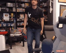 a man in a black t-shirt is standing in front of a bookshelf with the words think jules on the bottom right