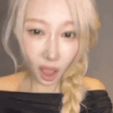 a woman with blonde hair is wearing a black off the shoulder top and making a funny face .