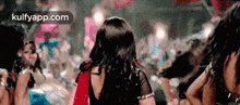 a woman in a red saree is dancing in a crowd of people at a party .