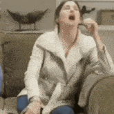 a woman is sitting on a couch with her mouth wide open