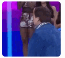 a man in a blue jacket is standing in front of a group of people .