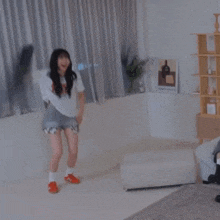 a woman is standing in a living room holding a pillow in her hand .