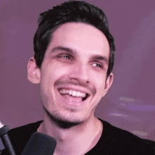 a man is smiling while holding a microphone in front of him