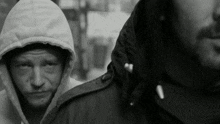 a man in a hooded jacket stands next to another man