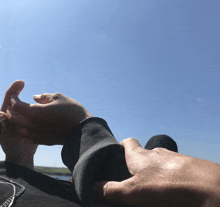 a person holding another person 's hand with a blue sky behind them