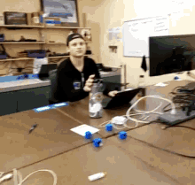 a man is sitting at a desk with a laptop and a bottle of water