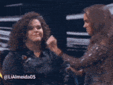 a woman with curly hair is being hugged by a man in a black jacket with the hashtag lialmeida05