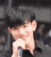 a young man is holding a microphone to his mouth and smiling .