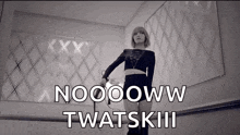 a black and white photo of a woman standing in a room with the words noooww twatskiii on the bottom