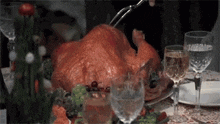 a turkey is sitting on a table with glasses of wine and a bottle of wine .