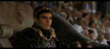 a man with a laurel wreath on his head is sitting in a chair